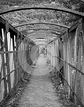 Old rusty metal pedestrian footbridge crossing a railway line