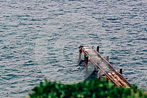 Old rusty metal pier photographed from above in the corner of the frame against the blue sea