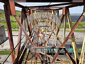 Old rusty metal structures. Old gantry crane. Descent down, passage.