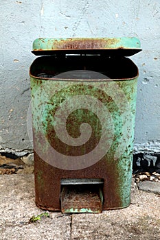 Old rusty metal waste bin with lid.