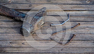 Old rusty nails and hammer on wooden background