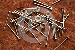 old rusty nails and nuts on a leather brown background, repair