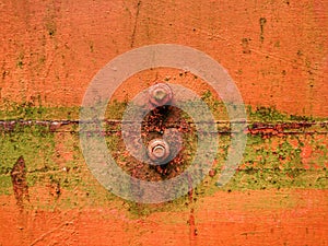 Old rusty nut and bolt with moss on orange background