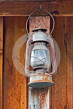 Old rusty oil-lamp under summer wooden shed