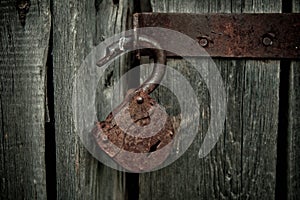 Old rusty opened lock without key. Vintage wooden door, close up concept photo