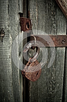 Old rusty opened lock without key. Vintage wooden door, close up concept photo