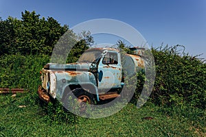 Old rusty overgrown truck. Abandoned Soviet tank car in ghost town