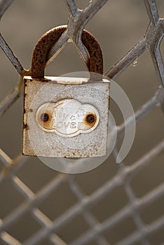 Old rusty padlock affixed on metal fence