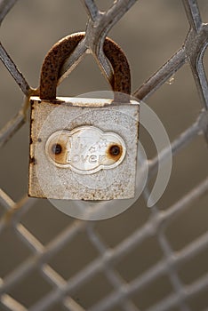 Old rusty padlock affixed on metal fence photo