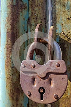 An old, rusty padlock with a chain hanging from the gate