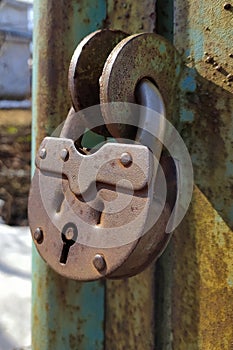 An old, rusty padlock with a chain hanging from the gate