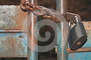 Old rusty padlock on the chain hangs on closed gates