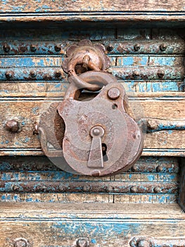 Old rusty padlock hanging on a dilapidated wooden door