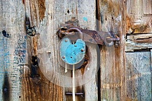 Old rusty padlock hanging on an old wooden door