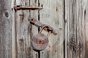 Old rusty padlock and latch on a wooden door