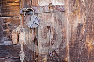 Old rusty padlock and latch on a wooden door