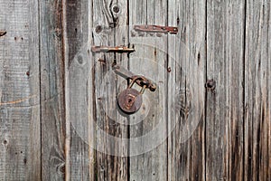 Old rusty padlock and latch on a wooden door