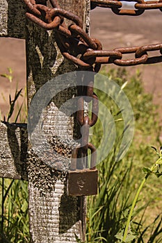 Old and rusty padlock tied to metal chains