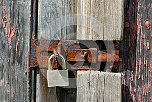 An old rusty padlock on wooden barn door