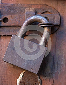 Old rusty padlock on a wooden door is a symbol of isolation incarceration