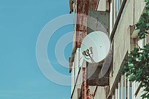 Old rusty panel house with a white satellite dish for television.