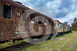 Old rusty passenger car with EMUs abandoned on railway tracks