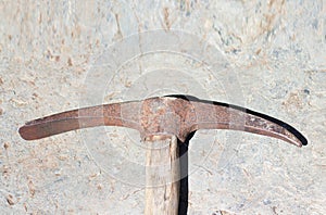 Old rusty pickaxe tool lies on a stone. Extraction of stone or gold with an iron pick with a wooden