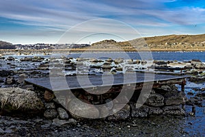 Old rusty pier made of wooden planks on top of rocky boulders at shores of Hafrsfjord fjord in Tananger