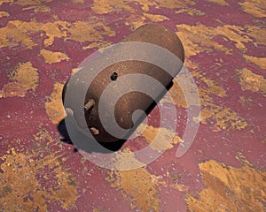 Old rusty propane tank on weathered metal sheet.