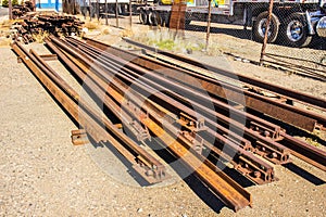 Old Rusty Railroad Rails Stacked By Side of Road