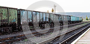 Old rusty railway cars stand on the tracks