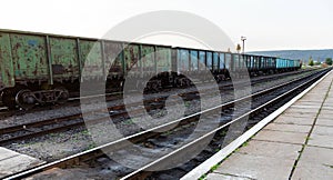 Old rusty railway cars stand on the tracks