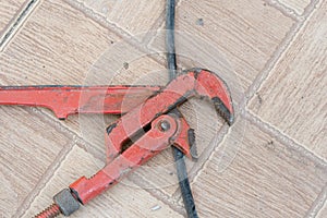 Old rusty red pipe wrench on concrete floor