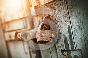 An old rusty retro padlock hangs on an old wooden gate, painted with blue paint. The secret is behind closed doors