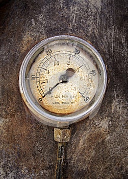 Old rusty round industrial pressure gauge with numbers round the dial