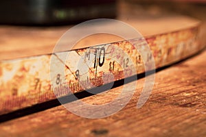 Old rusty ruler with black numbers on a working wooden table. vintage measuring tape close up. industrial background