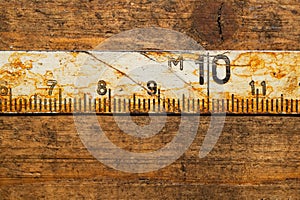Old rusty ruler with black numbers on a working wooden table. vintage measuring tape. industrial background