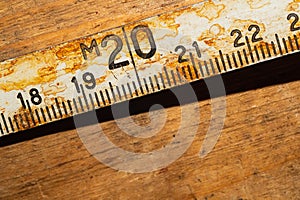 Old rusty ruler with black numbers on a working wooden table. vintage measuring tape. industrial background