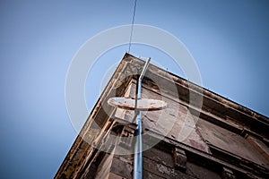 Old and rusty satellite dish and  and TV UHF antennas on display at the top of a residential building.