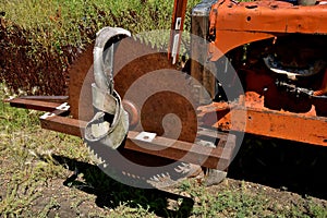 Old rusty saw blade mounted on an orange tractor front