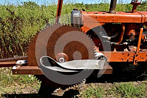 Old rusty saw blade mounted on an orange tractor front