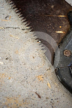 Old rusty saw on a stone floor, close-up