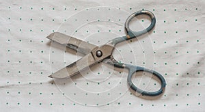 old rusty scissors on green polka dot background.