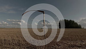old rusty scythe on harvested crop field and clouds motion  time lapse