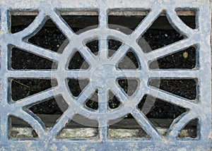 Old rusty sewer grate of unusual shape