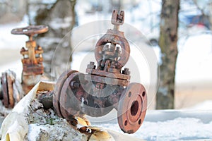 Old rusty shut-off valve on a heating pipe on a winter background