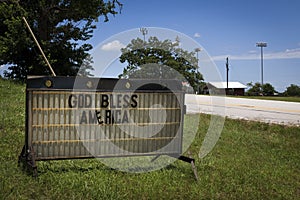 An old rusty sign with the words `God Bless America` by the side of a country road in rural Texas