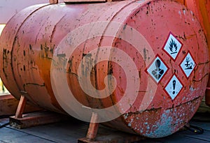 Old rusty silo tank containing hazardous substances, warning labels on the side, storage of dangerous liquids