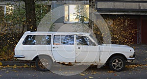 An old rusty Soviet car at the entrance of a residential building photo