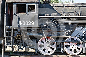 Old rusty steam locomotive beside a railway station platform. Retro train